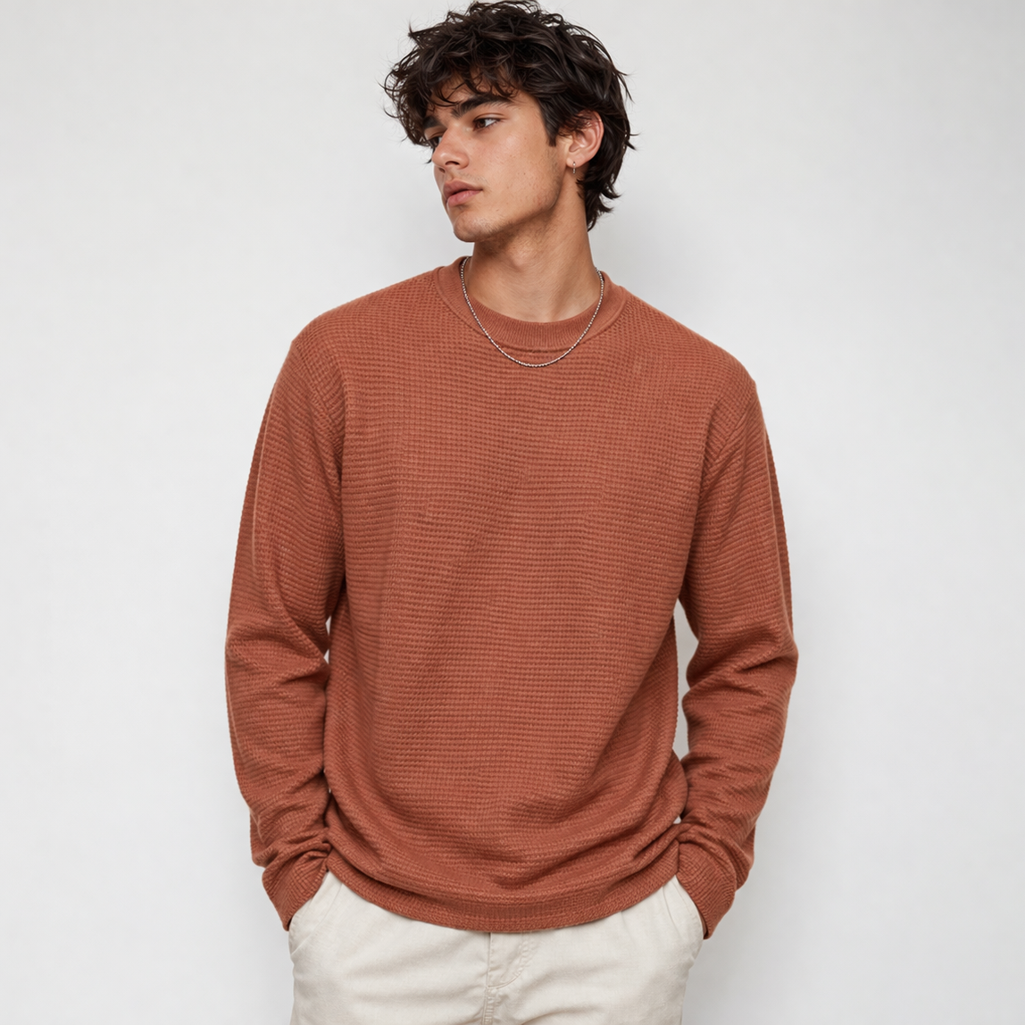 Man wearing a brown ribbed sweater against a white background